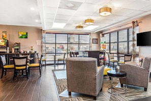 A modern hotel lobby with a bar area, seating, and large windows. - Quality Inn Memphis Airport (Memphis)