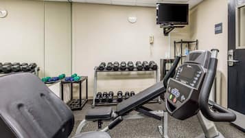 Un gimnasio con equipo de ejercicio, incluyendo cintas de correr, mancuernas y una bicicleta estática.
