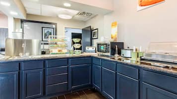 Una cocina moderna con armarios azul oscuro, un lavamanos de acero inoxidable, un microondas, un tostador y una cafetera.