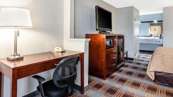 A hotel room with a desk, chair, television, and a bed.