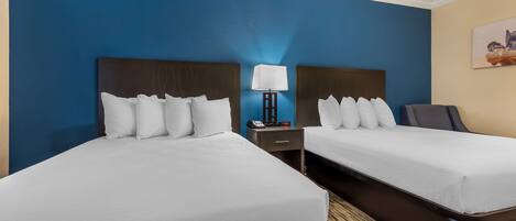 A hotel room with two beds, a nightstand with a lamp, and a painting on the wall.