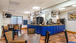 Un restaurant avec un comptoir bleu, des chaises en bois et un sol carrelé.