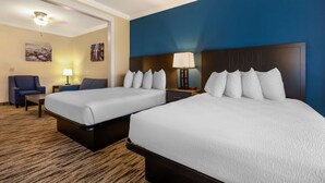 Une chambre d’hôtel avec deux lits, un bureau, une chaise et une lampe.