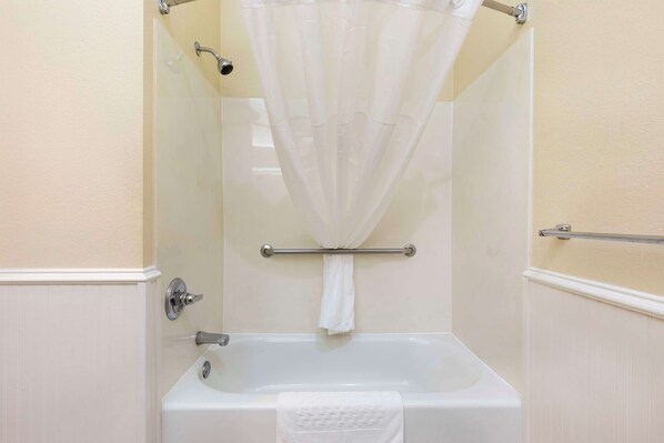 Ein Badezimmer mit Badewanne, Duschvorhang und Handtuchhalter.