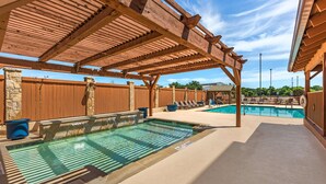 Un espace piscine extérieur abrité, doté d’une pergola, de piliers en pierre et de chaises longues.