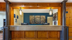 Un espace d’accueil agrémenté de panneaux muraux en bois, d’un comptoir en granit et de deux luminaires fixés au mur.
