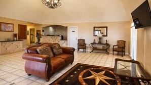 A spacious living room with a leather sofa, a star-patterned rug, a console table, and a flat-screen TV mounted on the wall.
