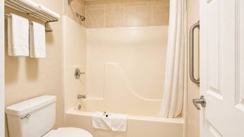 A bathroom with a toilet, bathtub, shower, and a towel rack.