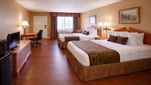 A hotel room with two beds, a desk with a computer, a TV, and a refrigerator.