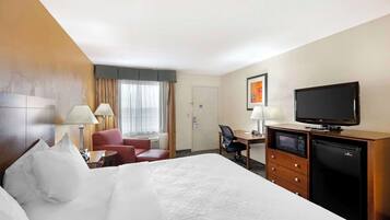 Une chambre d’hôtel avec un grand lit, un bureau avec un ordinateur, une télévision et un minibar.