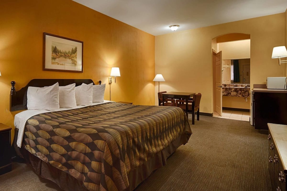 A hotel room with a bed, bedside tables, a desk, and a chair.
