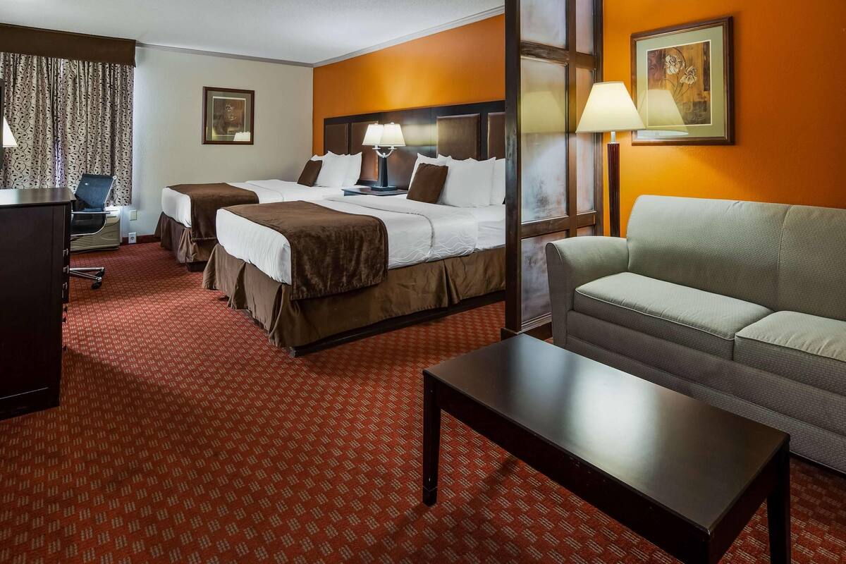 Une chambre d’hôtel avec deux lits, un canapé, un bureau et une lampe.