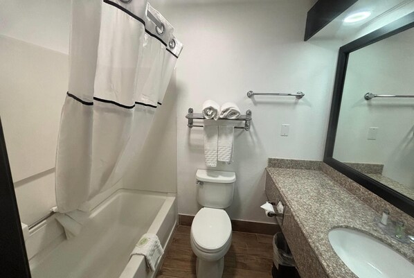 A bathroom with a bathtub, toilet, and sink. - Baymont by Wyndham Lubbock (Lubbock)