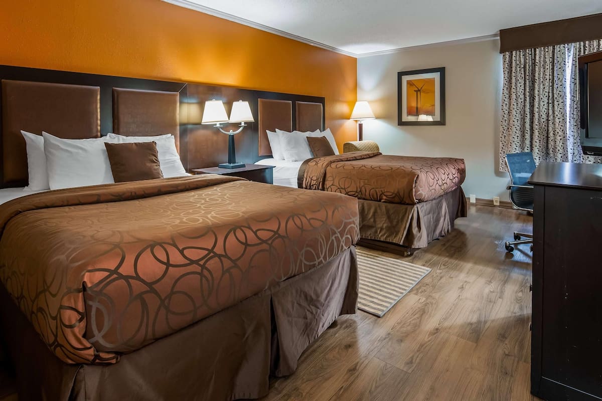 Une chambre d’hôtel avec deux lits, un bureau et une télévision.