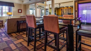 A hotel lobby with a reception desk, seating area with chairs, a patterned carpet, and a cross on the wall. - Baymont by Wyndham Lubbock (Lubbock)