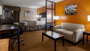 A hotel room with a bed, a desk, a chair, a sofa, and a TV. - Baymont by Wyndham Lubbock (Lubbock)