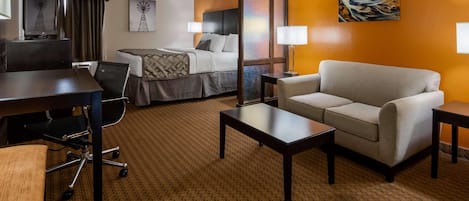 Una habitación de hotel con cama, escritorio, silla, sofá y televisor.