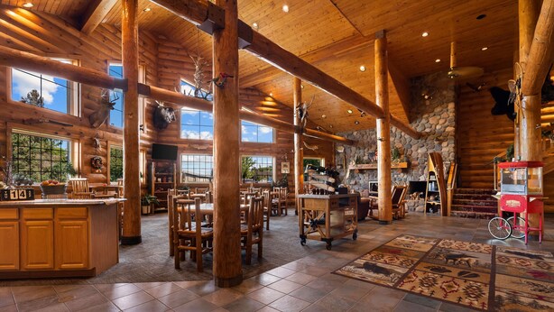 A spacious lodge interior with high ceilings, wooden beams, and a stone fireplace.