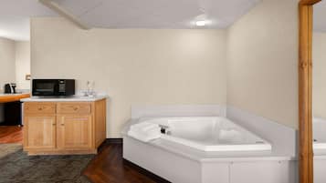 A modern bathroom with a freestanding bathtub, wooden cabinetry, and a microwave on a countertop.