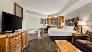 A hotel room with a bed, a TV, a desk, a chair, a bathroom, and a couch.