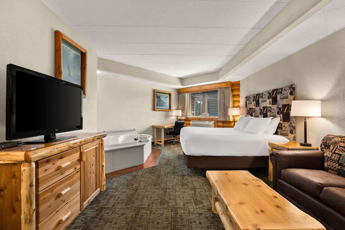 A hotel room with a bed, a TV, a desk, a chair, a bathroom, and a couch.