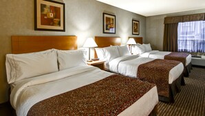 A hotel room with three beds, each with white linens and a brown patterned bedspread. There are framed pictures on the wall, a window with curtains, and a wooden headboard. - Canalta Hotel Hanna (Hanna)