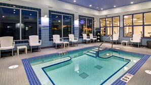 A swimming pool with chairs and a small table, surrounded by large windows. - Canalta Hotel Hanna (Hanna)
