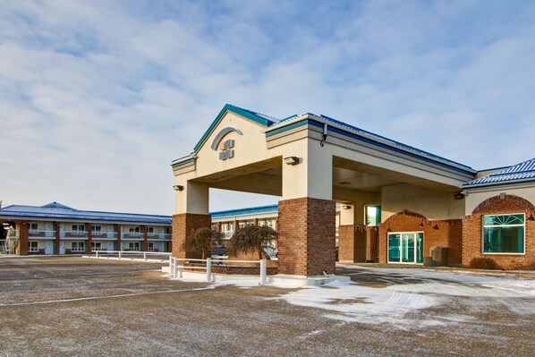 A hotel with a covered entrance, brick pillars, and a blue roof. - Canalta Hotel Stettler (Stettler)