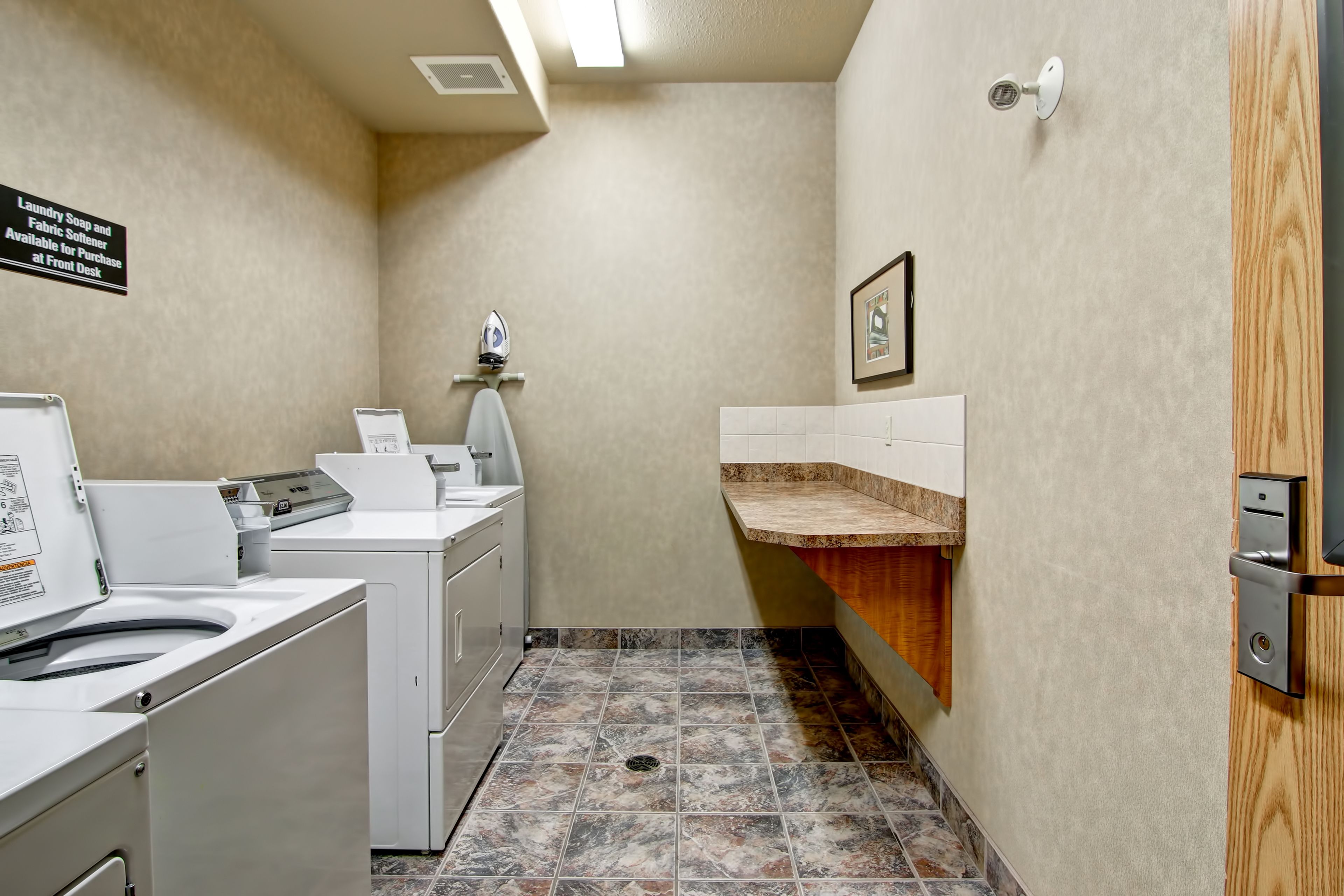 A laundry room with washers and dryers, a sink, and a small shelf.