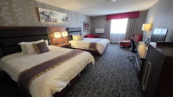 A hotel room with two beds, a desk, a chair, a TV, and a painting on the wall.