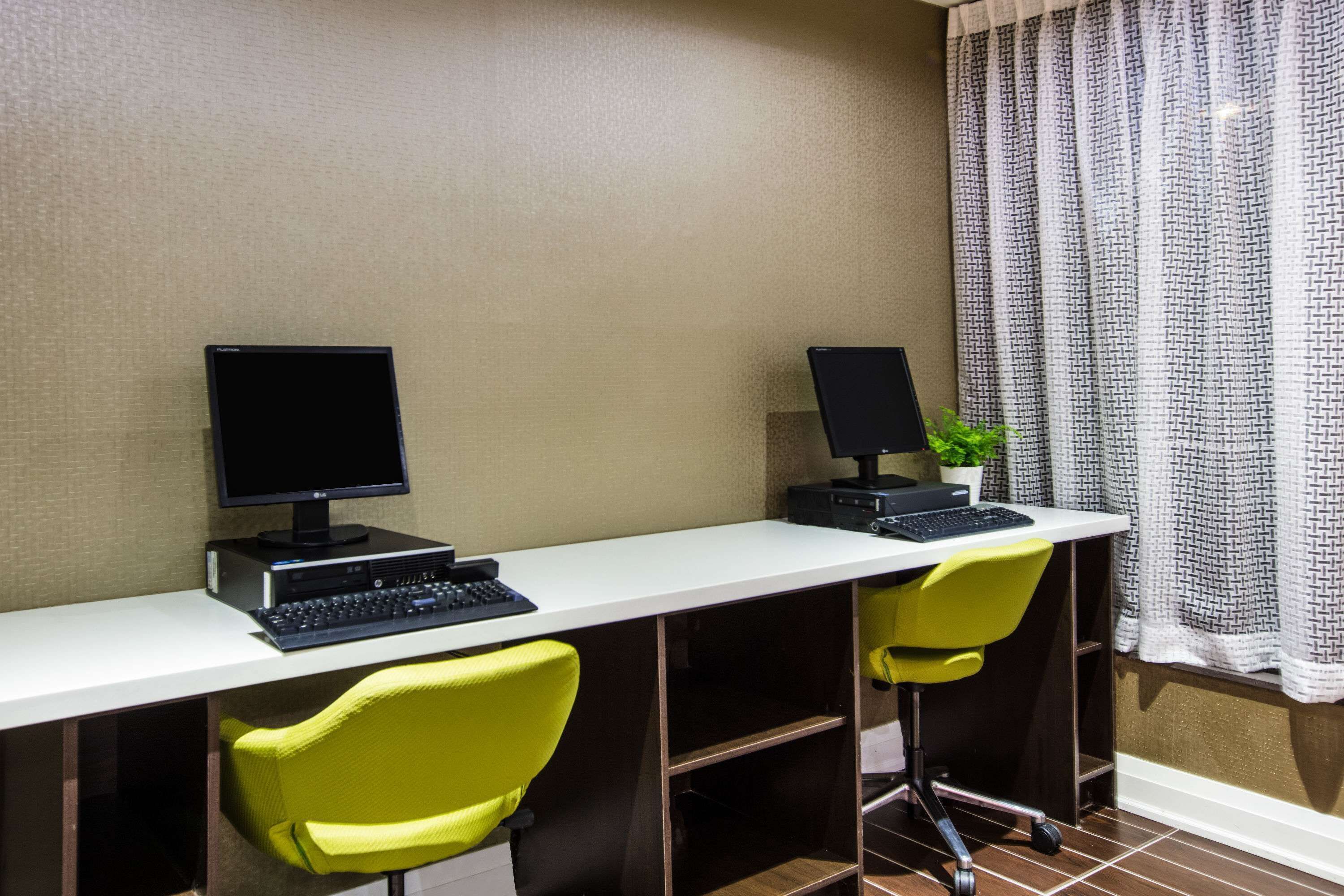 Un espace de travail comprenant deux bureaux, chacun équipé d’un ordinateur et d’un clavier, ainsi que deux chaises jaunes.