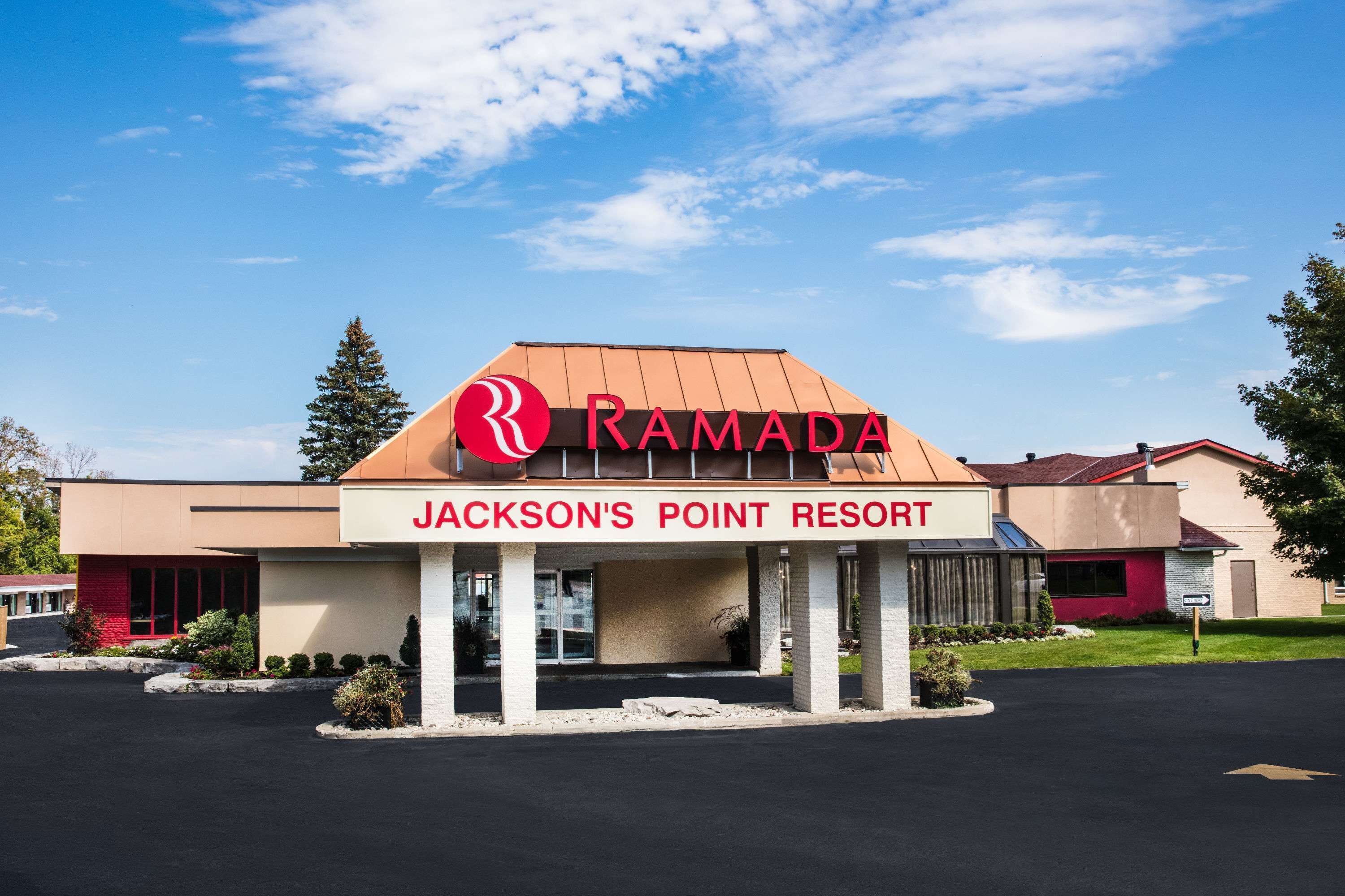 Un Resort Ramada Jackson's Point, con un logo rojo llamativo, un diseño de edificio moderno y un estacionamiento.