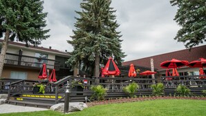 A hotel with outdoor seating, a staircase, and a large tree. - Ramada by Wyndham Jacksons Point (Georgina)