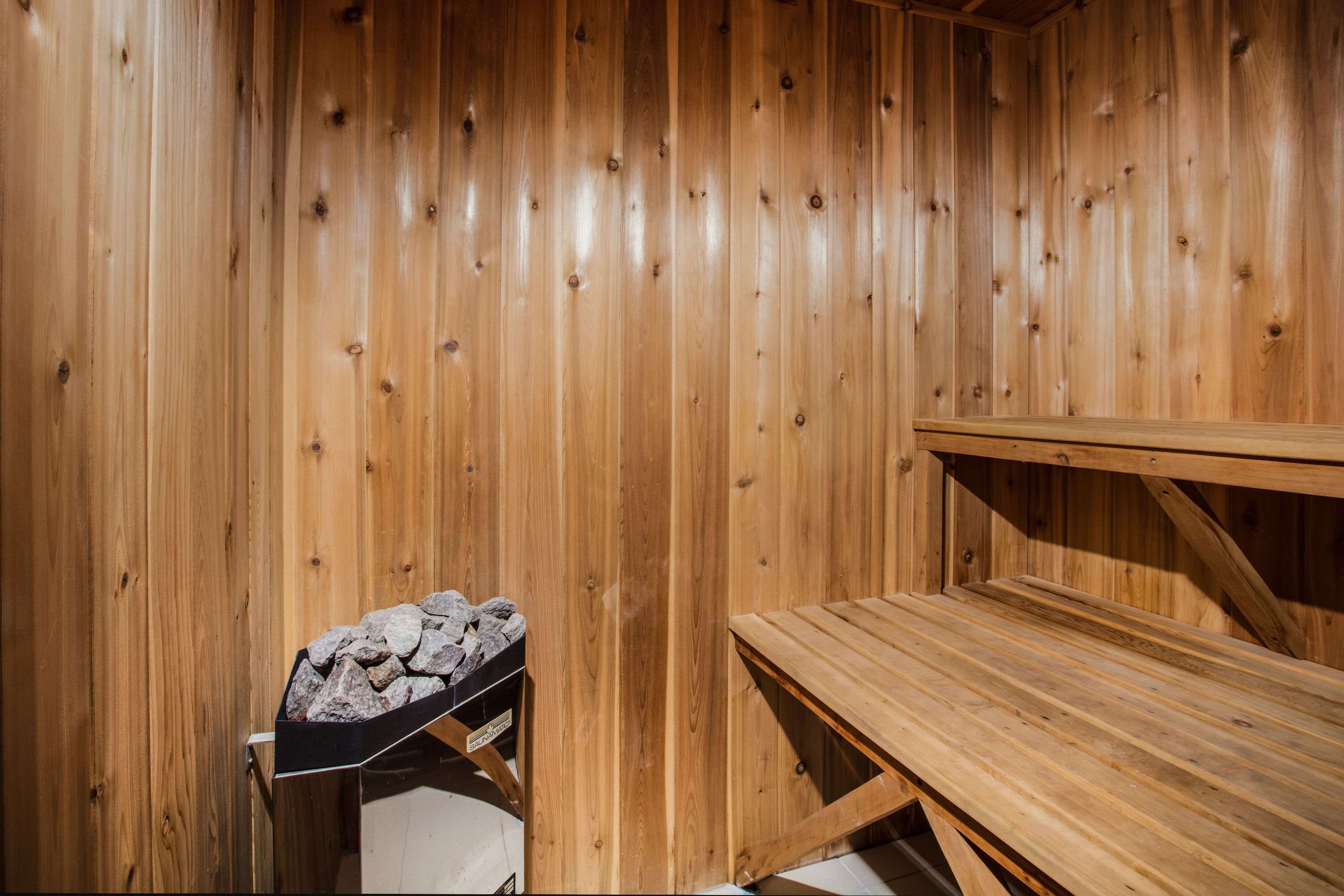 A wooden sauna room with a bench and a stone-filled container.