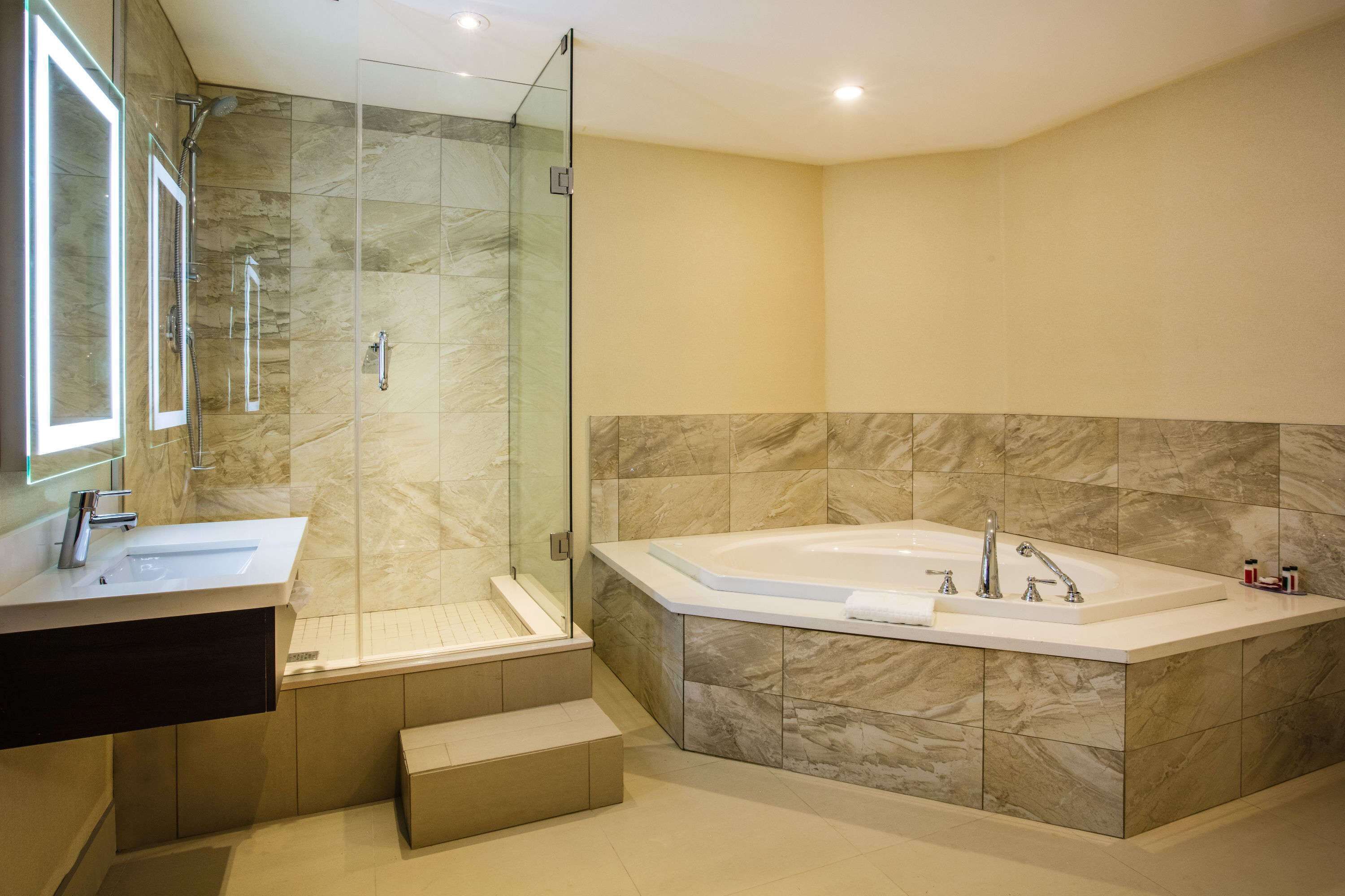 Un bany modern amb dutxa envidrada, banyera independent i un lavabo amb mirall.