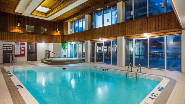 An indoor swimming pool with clear lane markings, a wooden ceiling, and large windows. - Ramada by Wyndham Jacksons Point (Georgina)