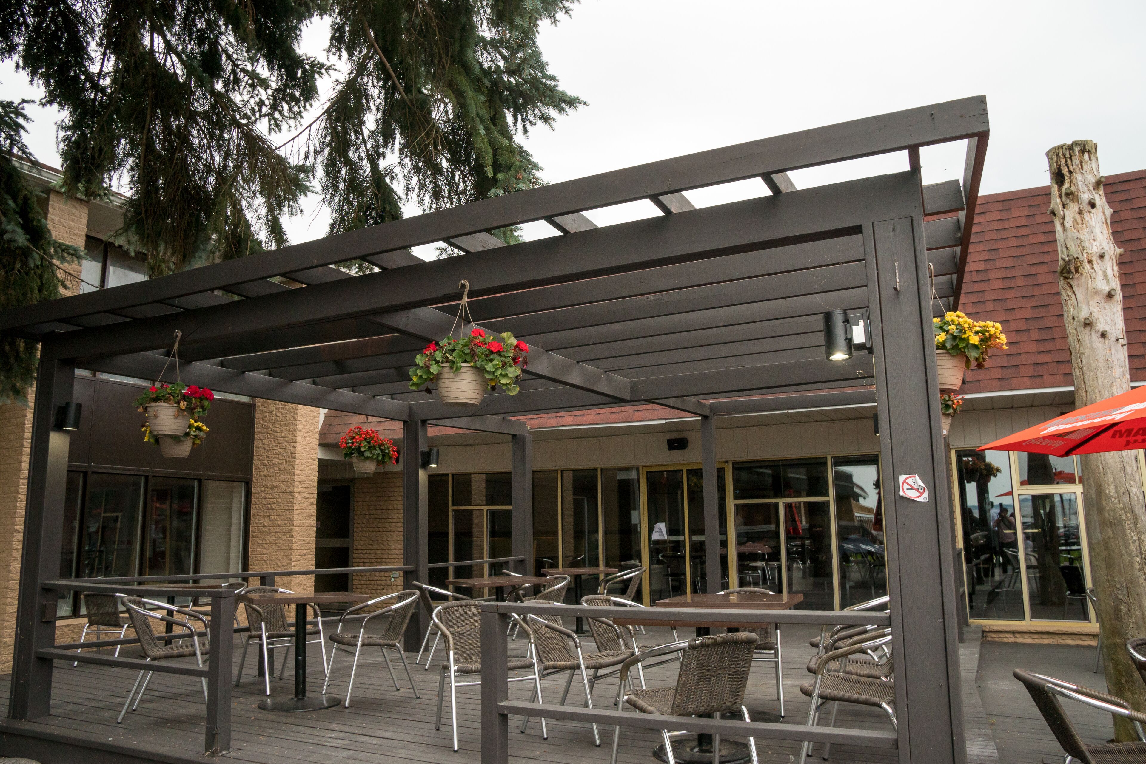 An outdoor patio with tables and chairs, hanging flower baskets, and a covered seating area.