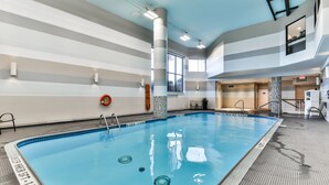 Una amplia piscina interior con carriles claramente marcados, una silla de salvavidas y vistas al cielo a través de grandes ventanales.