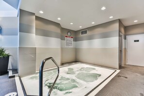 A spa area with a hot tub, a caution sign, and a clock on the wall. - Best Western Plus Cambridge Hotel (Cambridge)
