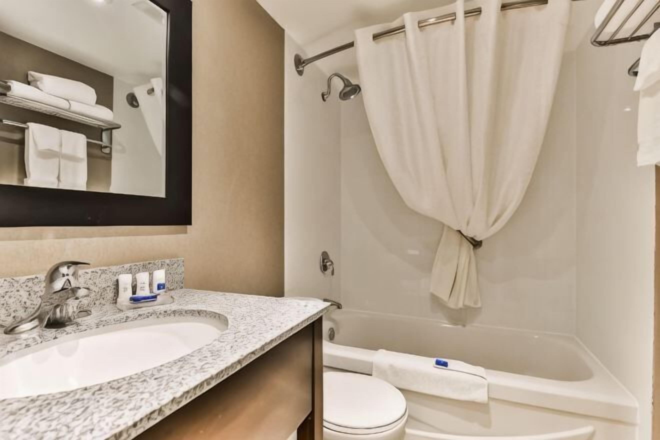 A bathroom with a sink, mirror, toilet, and shower.
