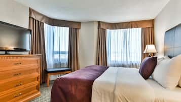 Habitación de hotel con cama, televisión, cómoda de madera y lámpara.