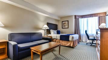 Een hotelkamer met een bed, een sofa, een bureau en een stoel.