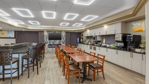 A modern restaurant with a long counter, multiple tables, and chairs. - Quality Inn & Suites (Brampton)