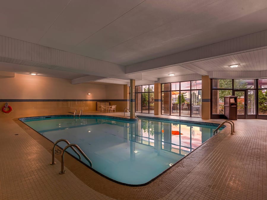 An indoor swimming pool with tiled flooring, a metal ladder, and a lifebuoy.