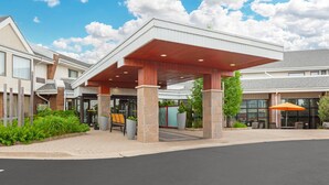A hotel entrance with a covered outdoor area, a reception desk, and a seating area with umbrellas. - Quality Inn & Suites (Brampton)