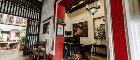 Interior com piso de madeira, um banco, uma mesa e um lustre.