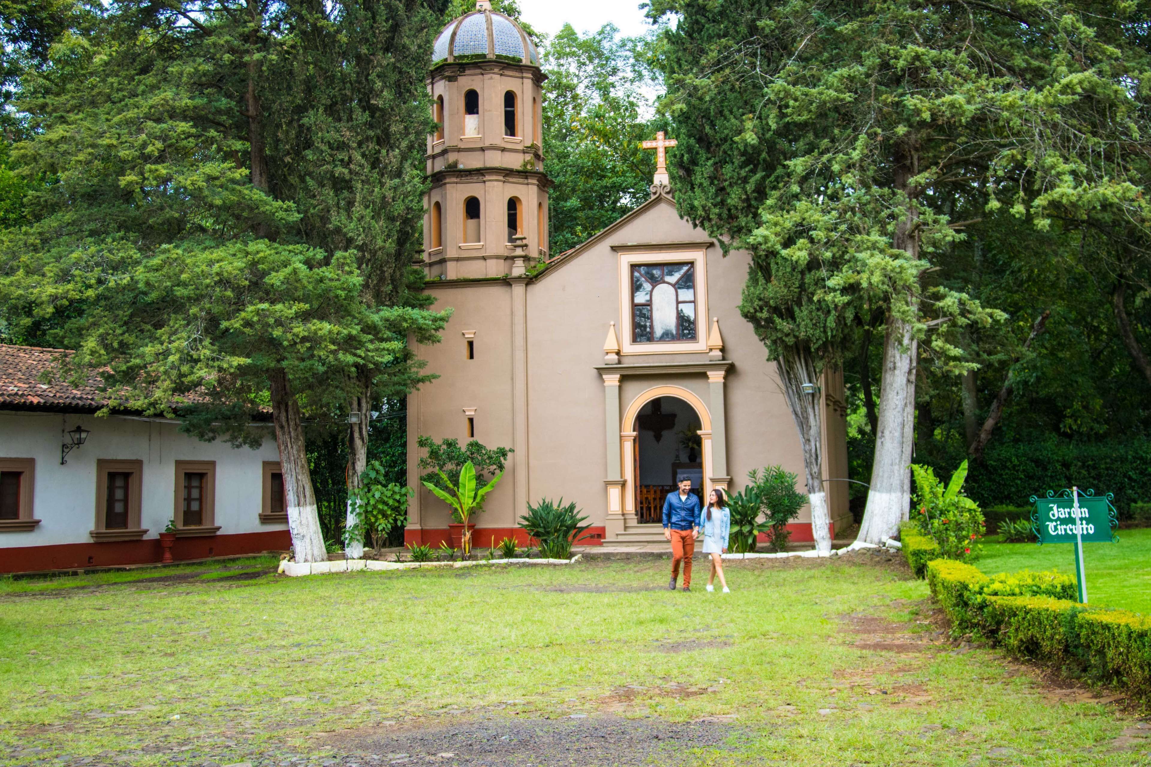 A church with a bell tower, surrounded by greenery and a sign reading "Jardim Circulo".