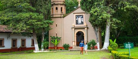 A church with a bell tower, surrounded by greenery and a sign reading "Jardim Circulo".