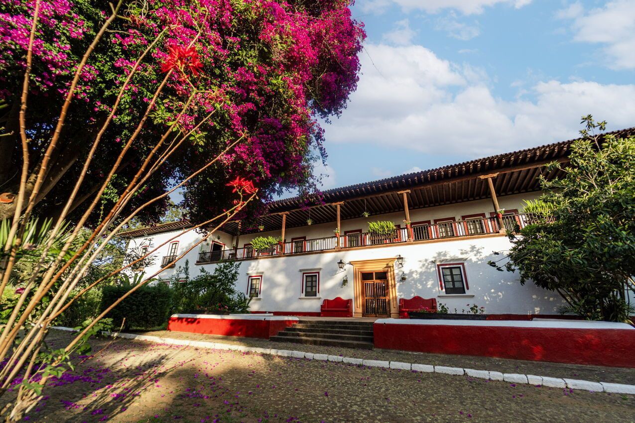 Un edificio tradicional con fachada blanca, detalles en rojo y un balcón.