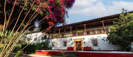 Un edificio tradicional con fachada blanca, detalles en rojo y un balcón.